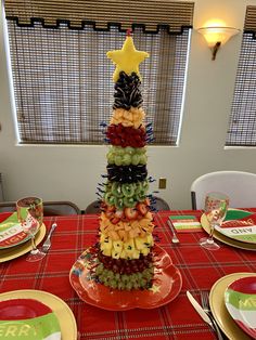 a christmas tree made out of fruit sitting on top of a red cloth covered table