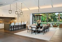 a dining room table with white chairs next to an open kitchen and living room area