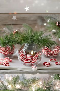 some candy canes are in a glass bowl on a table next to christmas decorations