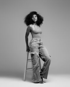 a black and white photo of a woman sitting on a stool