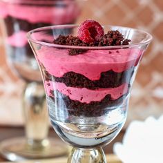 two desserts with raspberries and oreo cookies in glasses on a table