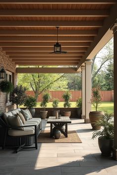 a covered patio with couches and potted plants