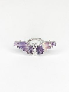 a silver ring with purple and white butterflies on the front, set against a white background