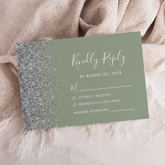 a green and silver glitter wedding rsp card on top of a white bed sheet