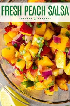 a glass bowl filled with chopped fruit and garnished with cilantro, limes, and onions