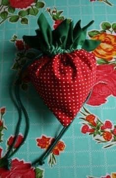 a red and white polka dot bag sitting on top of a blue flowered table cloth