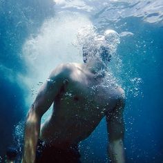 a man swimming in the ocean with his shirt off and head above water's surface