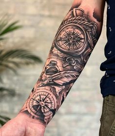 a man's arm with a clock and compass tattoo on it