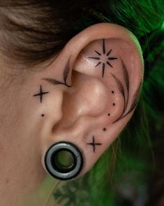 a woman's ear has a star and cross tattoo on it