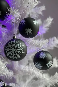 three black and white ornaments hanging from a christmas tree in front of a purple background