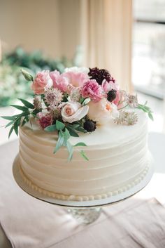 a close up of a cake with flowers on the top and bottom, sitting on a table in front of a window