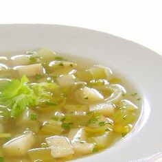 a white bowl filled with soup and garnished with parsley on the side