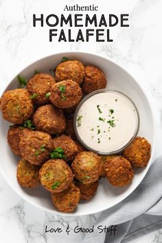 a white bowl filled with fried meatballs next to a small cup of ranch dressing