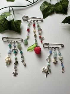 four different types of hair clips with fruit and beads hanging from them on a white surface