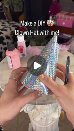 a person holding a phone in their hand with the text make a diy clown hat with me