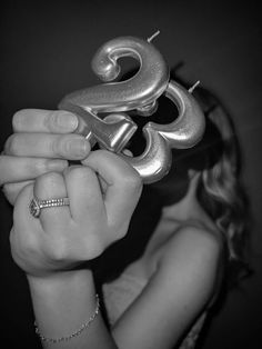 a woman holding up two silver objects in front of her face with the letter g on it