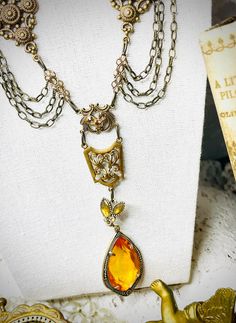 Victorian Revival Amber Teardrop Laviler Necklace~ Lightweight Teardrop is  amber colored and is prong set in the setting - setting has tiny sparkling stones at base , brass gorgeous chain adorned with various filigree sections and champagne stones !  18" necklace with an additional 2" for adjusting length ~also ends in a champagne bead ! pendant adds another 4 1/2" for a very stunning piece !  romantic and sweet piece of jewelry ! Add a touch of  vintage ! New Old Stock 1980s never worn  We shi Vintage Amber Necklaces For Festivals, Vintage Yellow Brass Jewelry, Gold Vintage Charm Necklace For Festival, Gold Necklace With Vintage Charm For Festival, Festival Jeweled Gold Jewelry, Gold Jeweled Festival Jewelry, Gold Jeweled Dangle Necklaces, Gold Jeweled Jewelry For Festivals, Victorian Gold Teardrop Necklace