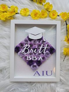 a purple and white graduation decoration in a frame