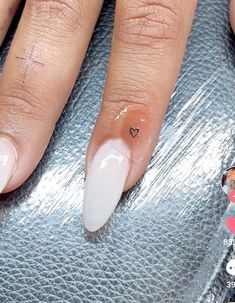 a woman's hand with white fingernails and heart shaped nail designs on it,