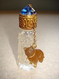 a small glass bottle with a bear charm on it