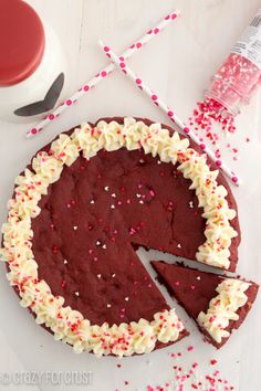 a chocolate cake with white frosting and sprinkles next to a knife