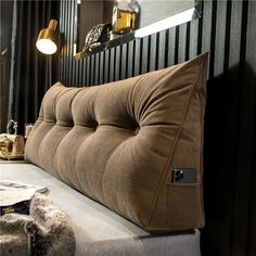 a large brown pillow sitting on top of a bed next to a wall mounted mirror