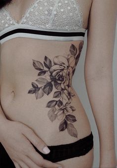 a woman's stomach with flowers and leaves on the side, in black and white