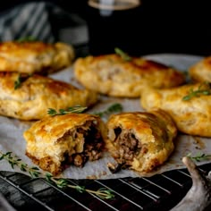 some meat and cheese pastries are on a grill with garnishes around them