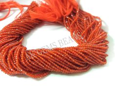 an orange necklace with beads and tassels on a white surface, close up