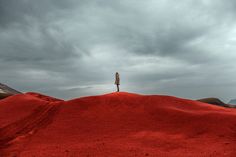 a person standing on top of a red hill