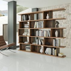 a book shelf with many books on it in a living room next to a window