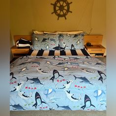 there is a bed with blue and white dolphin sheets on it, along with a ship wheel