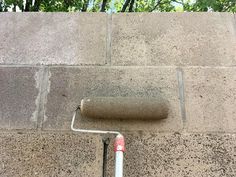 a pipe on the side of a building next to a brick wall with trees in the background