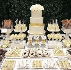 a table topped with lots of desserts covered in white frosting and gold decorations