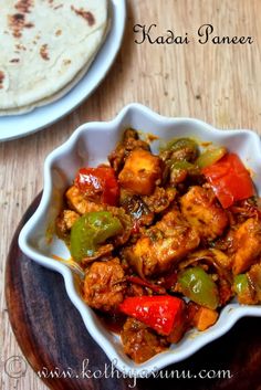 a white bowl filled with chicken and peppers next to a tortilla on a wooden table