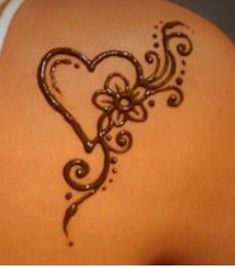 the back of a woman's stomach with henna tattoos on it and a heart shaped