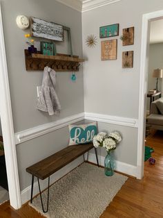 a wooden bench sitting in the corner of a room next to a wall with pictures on it