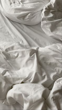 an unmade bed with white sheets and pillows