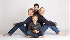 the family is posing for a photo in front of a white background with their arms around each other