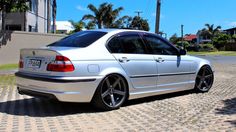 a silver car parked on the side of a road next to palm trees and buildings