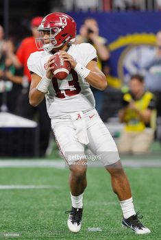 a football player holding a ball in his hands on the field with people watching him