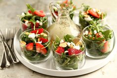 salad with strawberries, spinach and feta cheese in small glasses on a tray