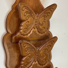 a wooden wall hanging with two butterflies on it's sides and an ornately carved design