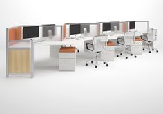 an office cubicle with four computer screens and two desks, all in different colors