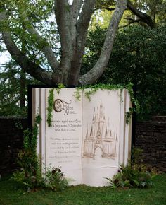 an open book sitting in the grass next to a tree