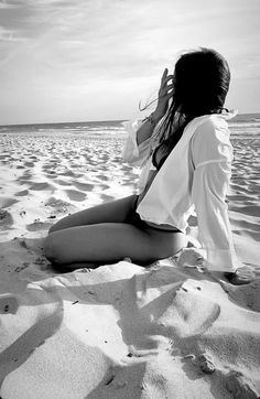 a woman sitting on top of a sandy beach