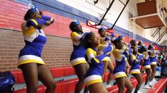 cheerleaders in blue and yellow uniforms perform on the sidelines at a basketball game