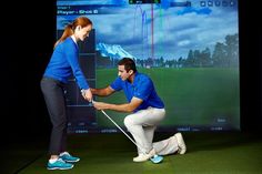 a man and woman playing golf in front of a screen