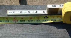 a measuring tape is on top of a piece of wood next to a yellow meter