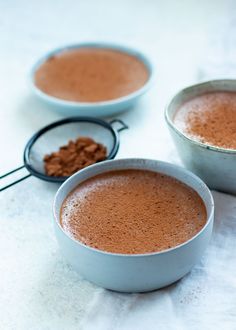 two white bowls filled with chocolate and some cocoa powder